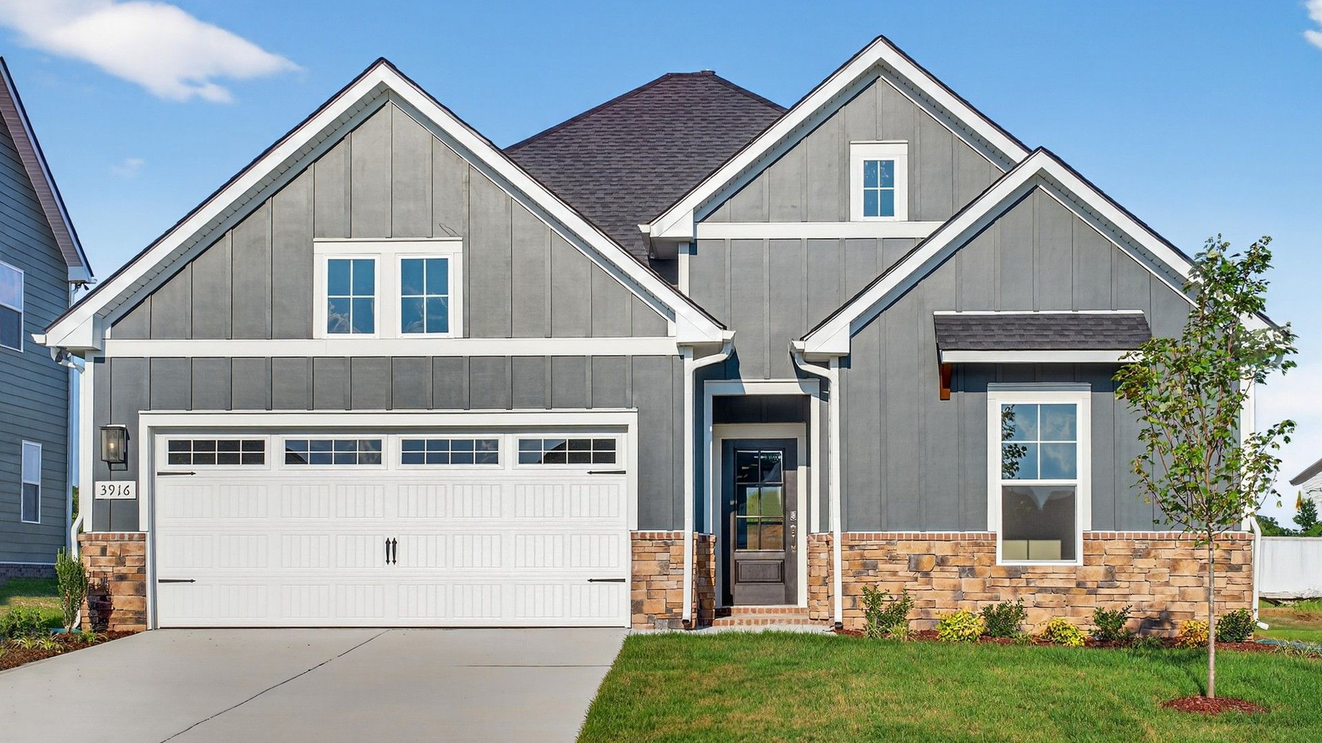 Modern Gray House with Stone Accents at Belmont, McClure Farms:Elegant gray facade with stone details and gabled roof offers timeless luxury. Belmont, McClure Farms.