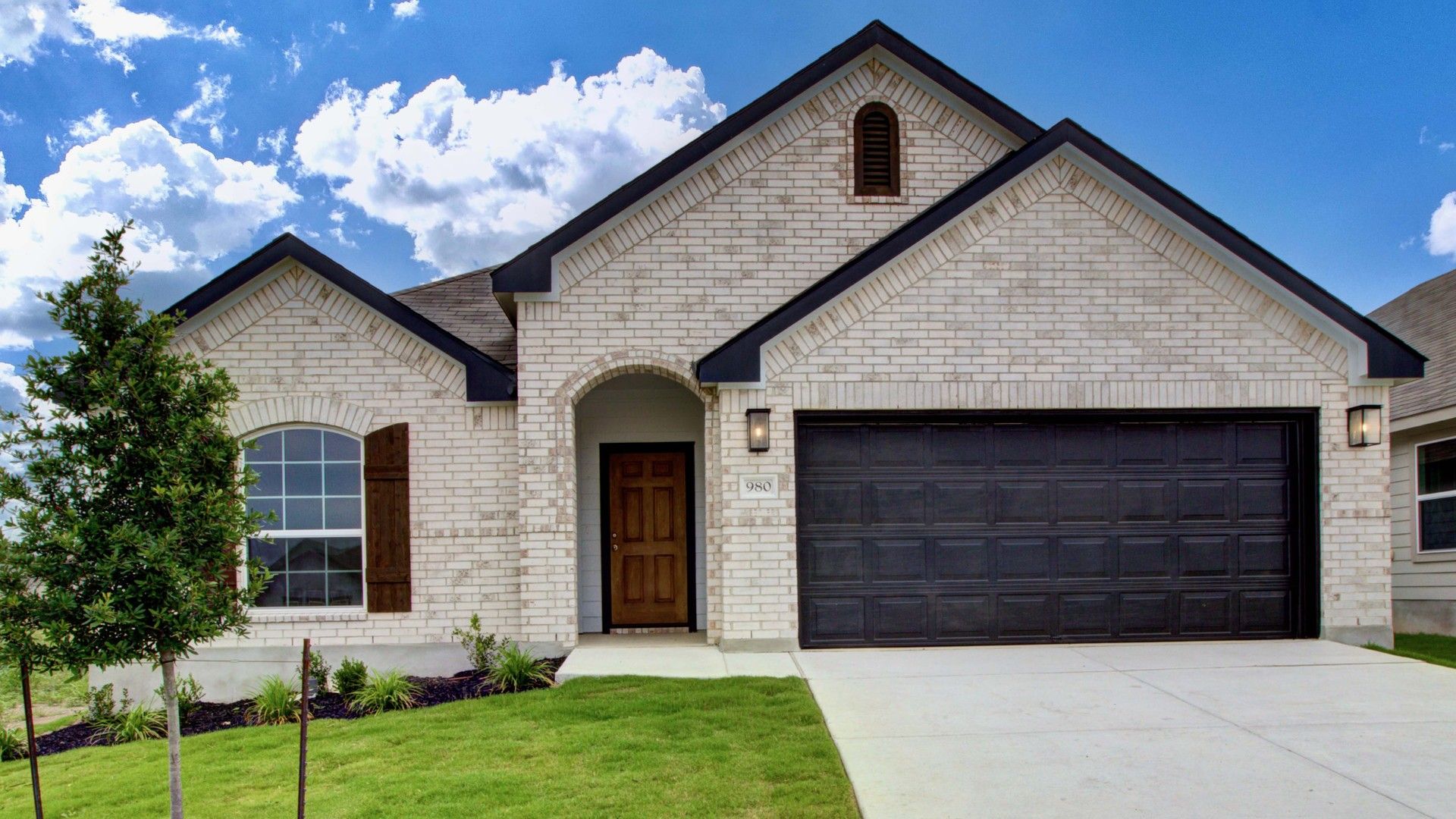 Brick House with Garage in Cloud Country:Elegant brickwork and arched window define this Cloud Country residence's refined curb appeal.