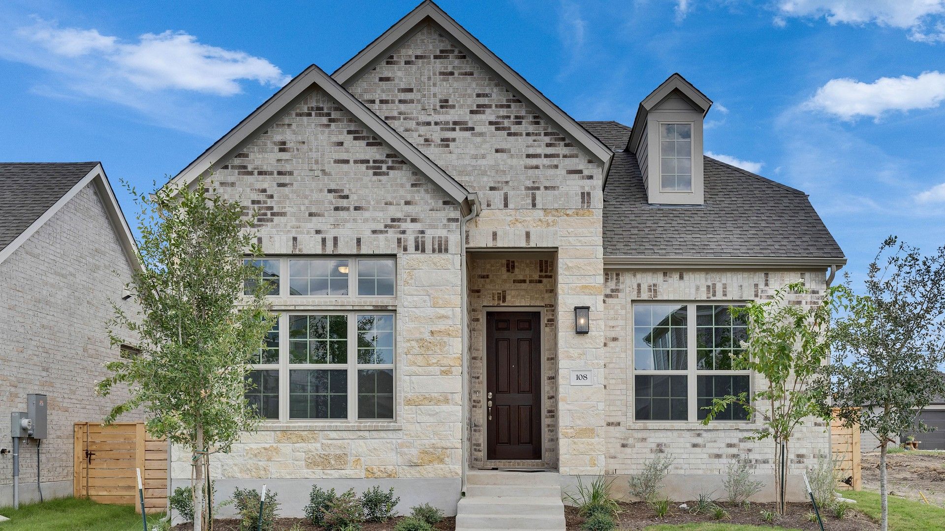Elegant Brick and Stone Residence with Dormer Windows:Revel in the exquisite blend of brick and stone facades, complemented by elegant dormer windows in a serene setting.