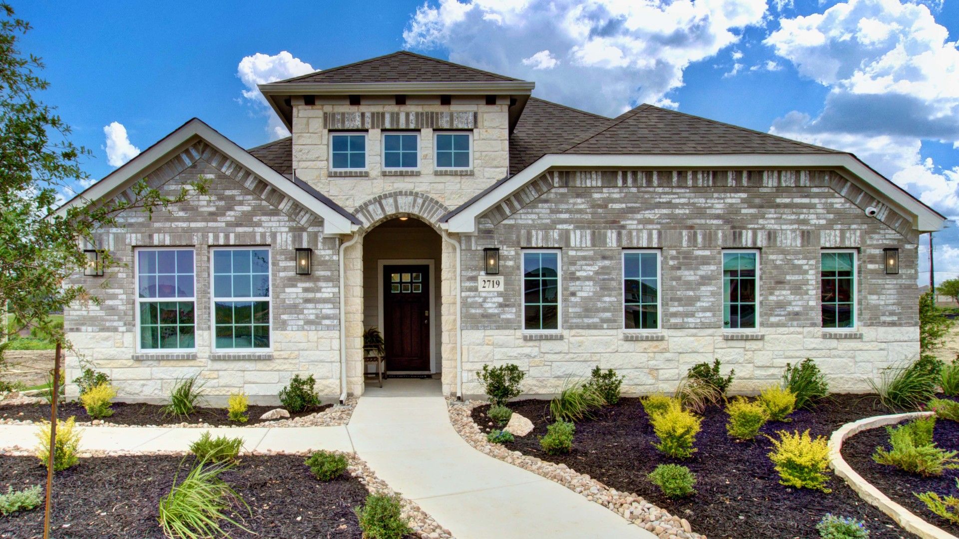 Prairie Green Brick Home with Arched Entrance and Manicured Landscape:Elegant brick facade with arched entrance and pristine landscaping in Prairie Green community.