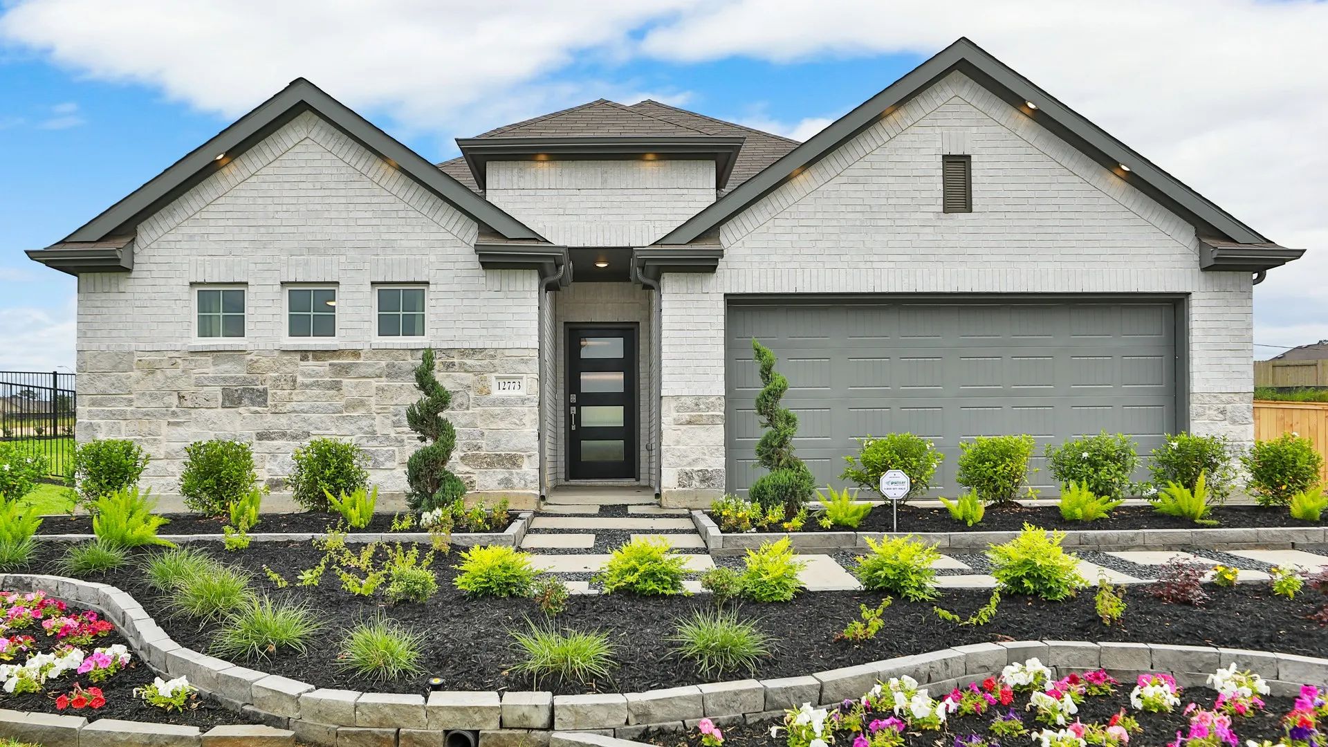 Elegant Brick Home with Stone Details in Whisper South Community:Whisper South home showcases exquisite brickwork and stone accents, complemented by lush, curated gardens.