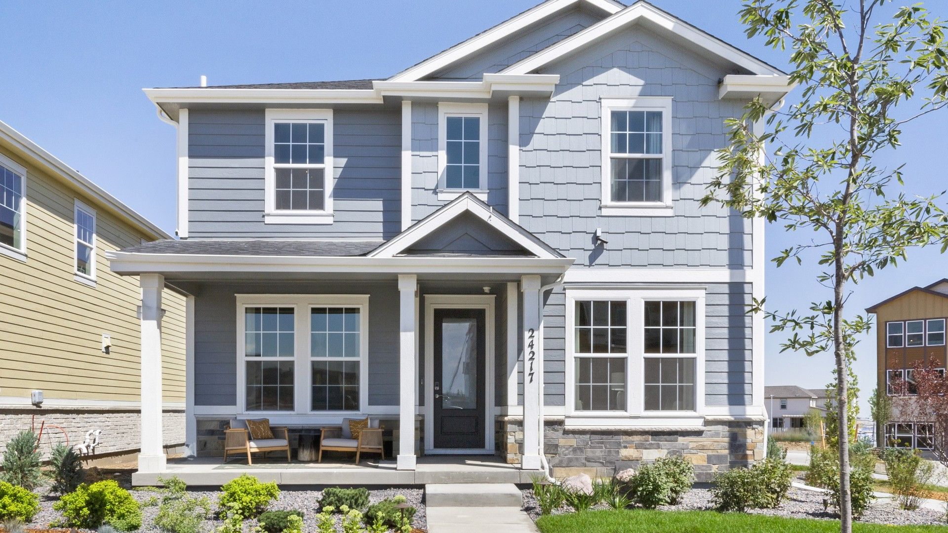 Two-Story Blue House with Porch in Windler Community:Elegant two-story home with a charming porch and striking stone facade in Windler community.
