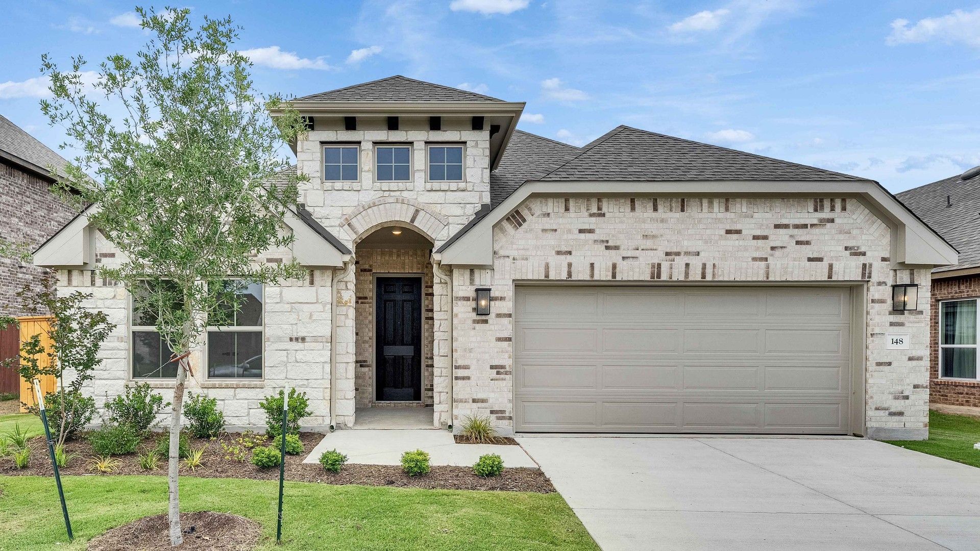 Elegant Home at Oaks at San Gabriel - Stone Exterior, Arched Entrance:Sophisticated stone façade, arched entrance, and elegant gabled roof define this Oaks at San Gabriel residence.