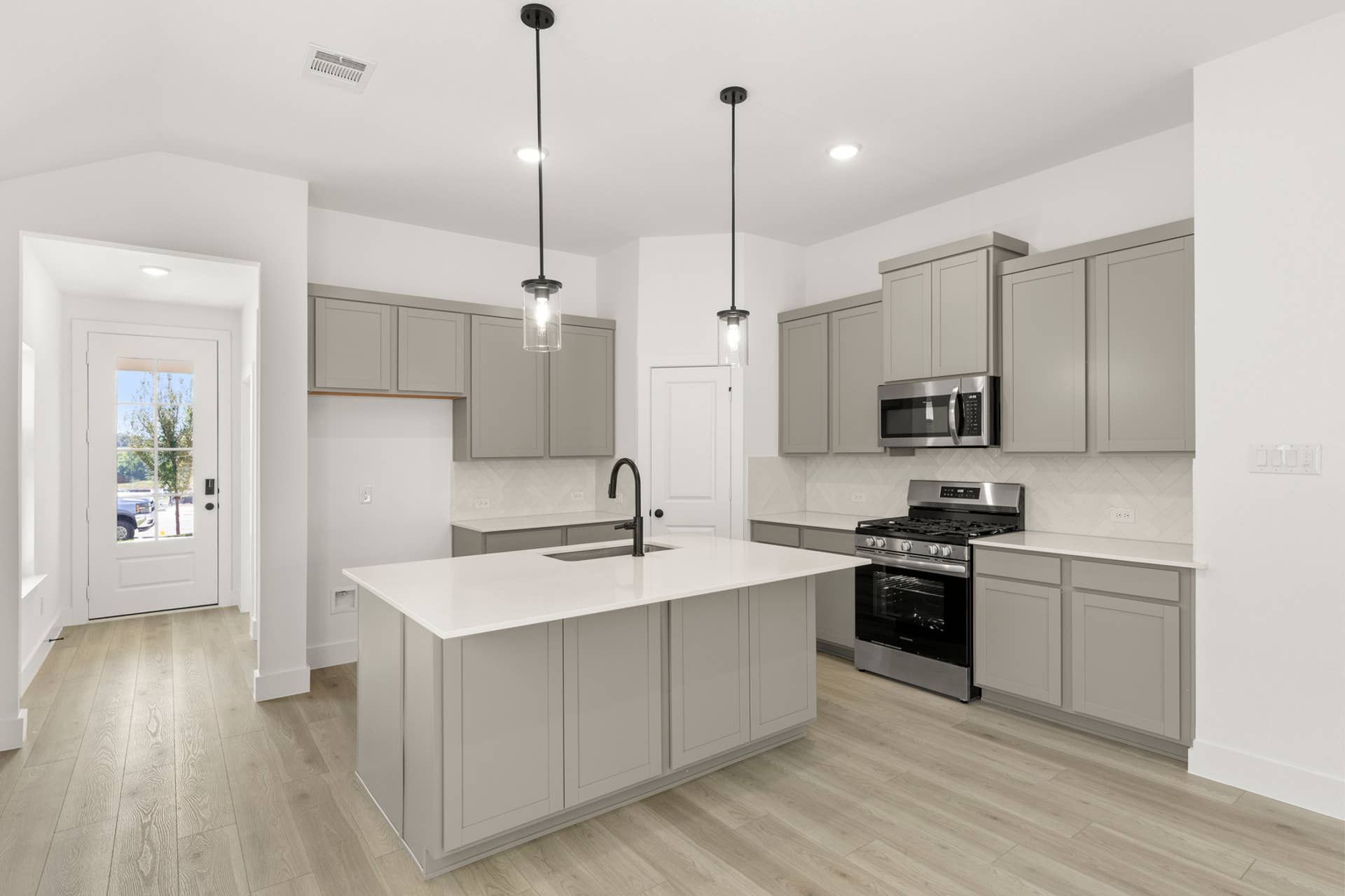 Interior Image:Modern kitchen with gray cabinets, island, and stainless steel appliances.