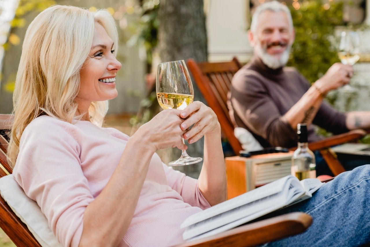 two people enjoying a glass of white wine outside:two people enjoying a glass of white wine outside