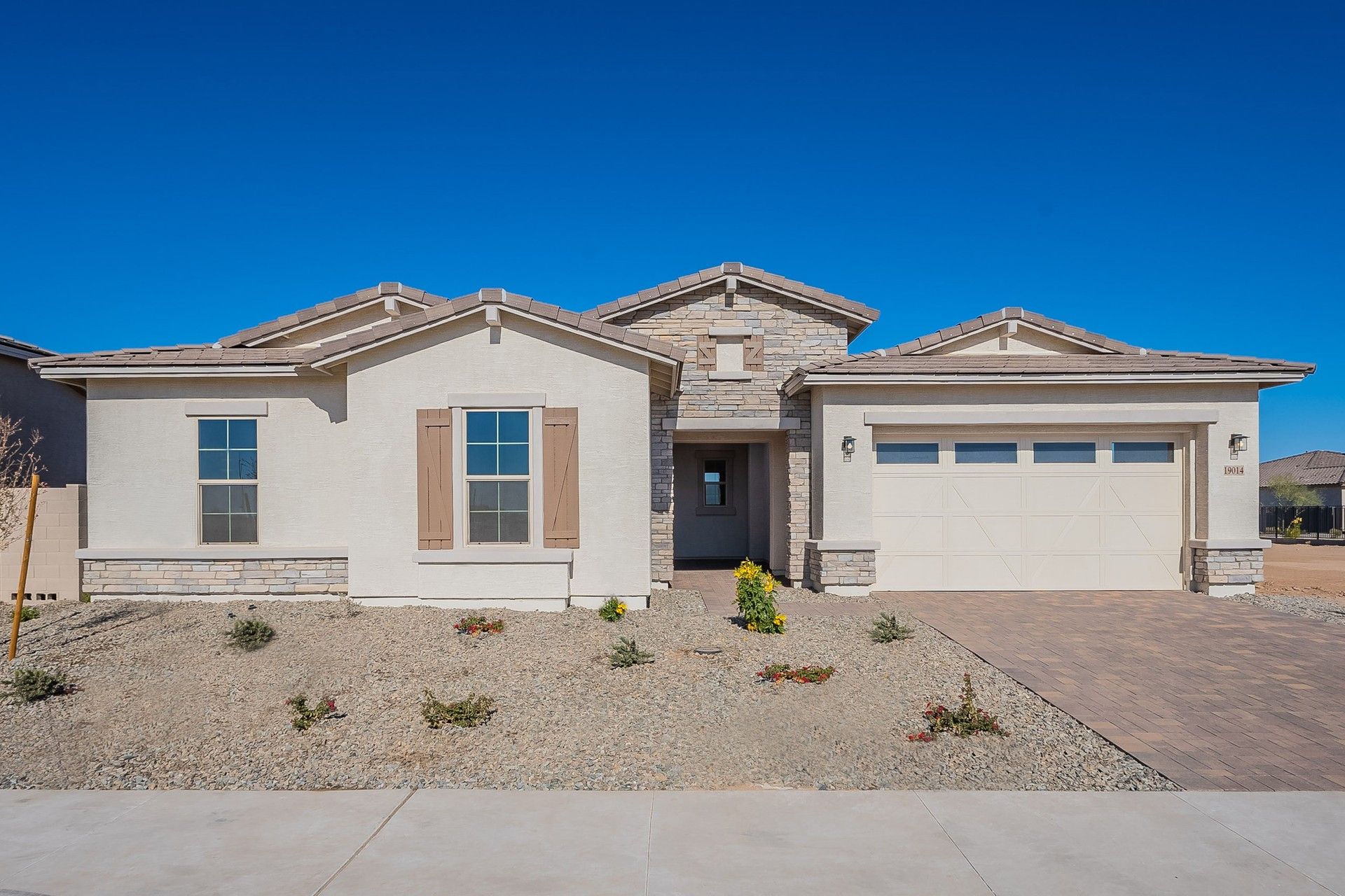 Modern Single-Story Home with Stone Accents in Granada, Windrose:Elegant stone detailing and desert landscaping enhance this Windrose home's sophisticated charm.