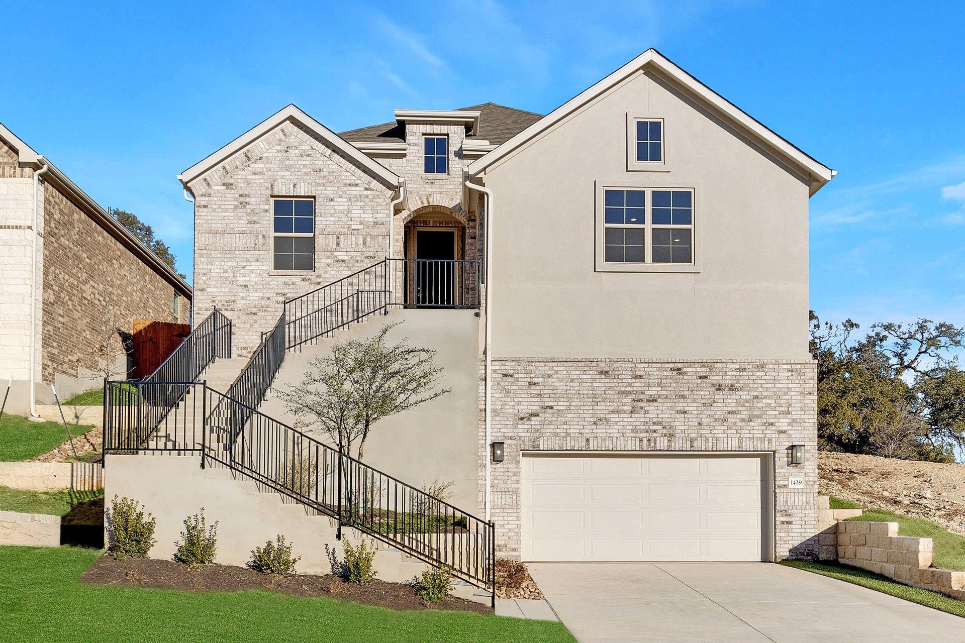 Modern Brick House at Retreat at San Gabriel with Spacious Garage Entry:Elegant brick façade with expansive windows and a bold entry staircase in Retreat at San Gabriel.