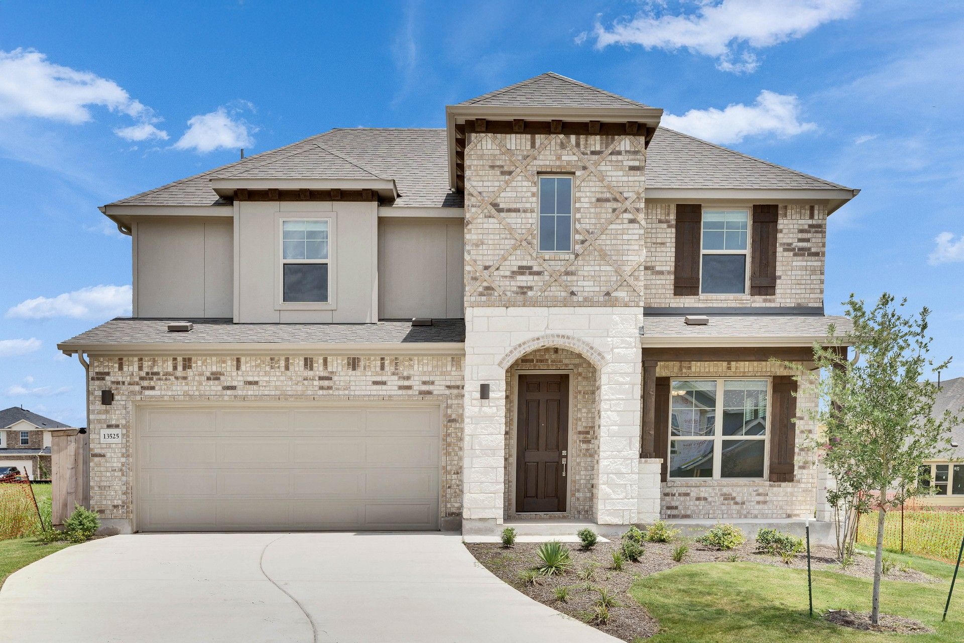 Two-Story Brick Home with Arched Entry in Briarwood:This Briarwood estate boasts a striking brick facade, arched doorway, and premium wooden shutters for timeless elegance.