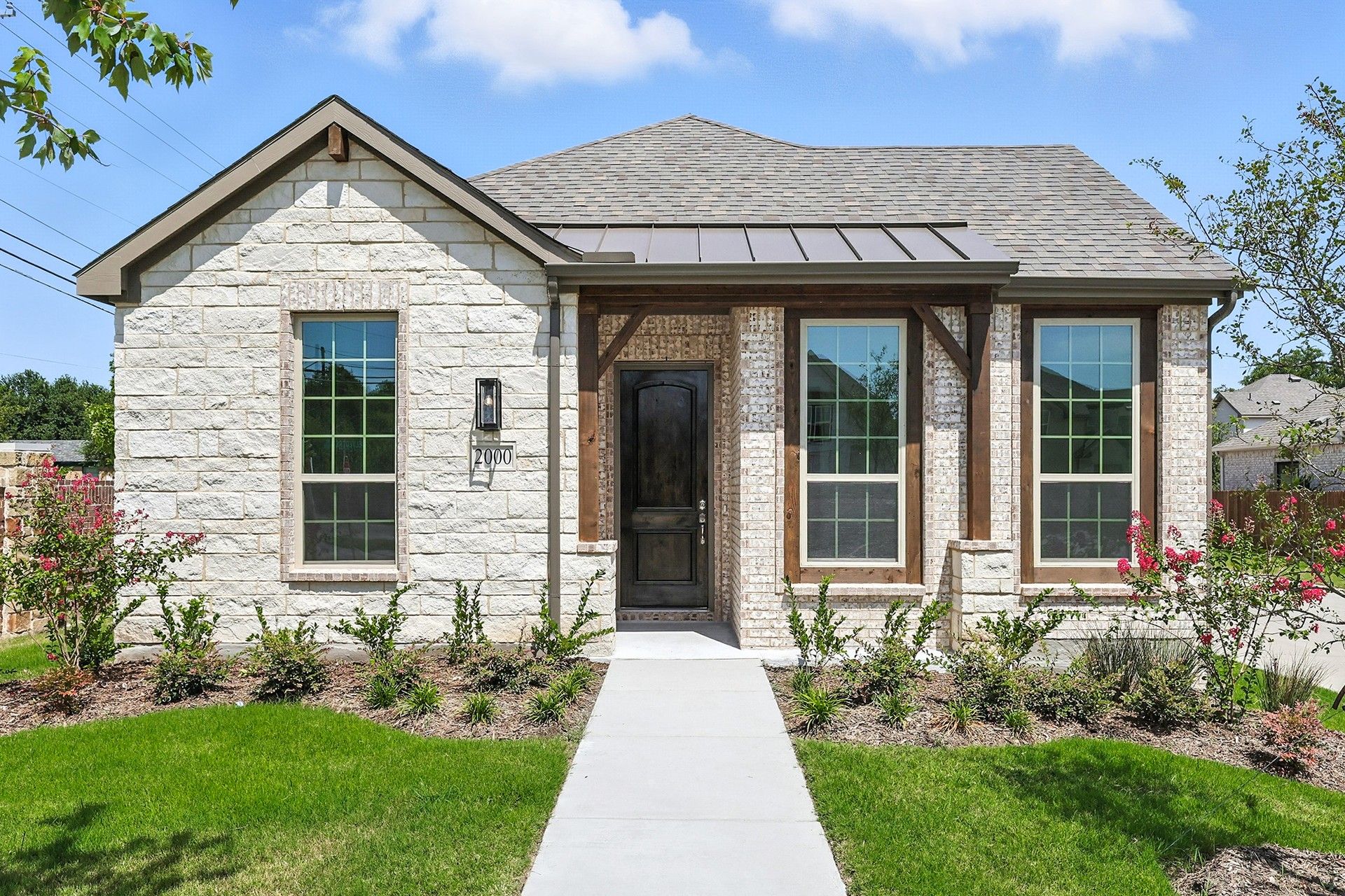 Stone Cottage Exterior in Carroll II at Heritage Park:Experience elegance with this stone facade, gable roof, and lush landscaping in Carroll II at Heritage Park.