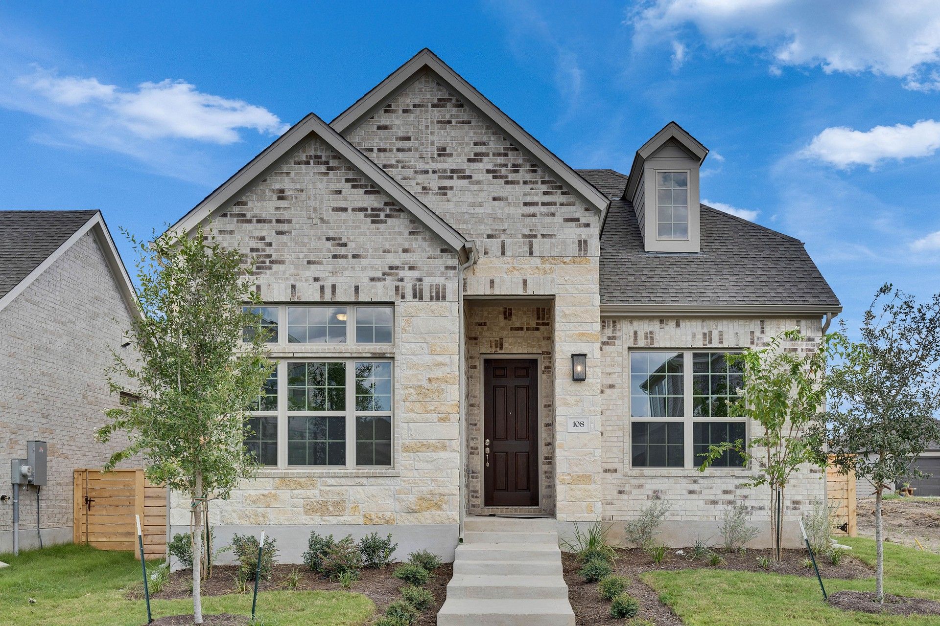 Elegant Brick and Stone Residence with Dormer Windows:Revel in the exquisite blend of brick and stone facades, complemented by elegant dormer windows in a serene setting.