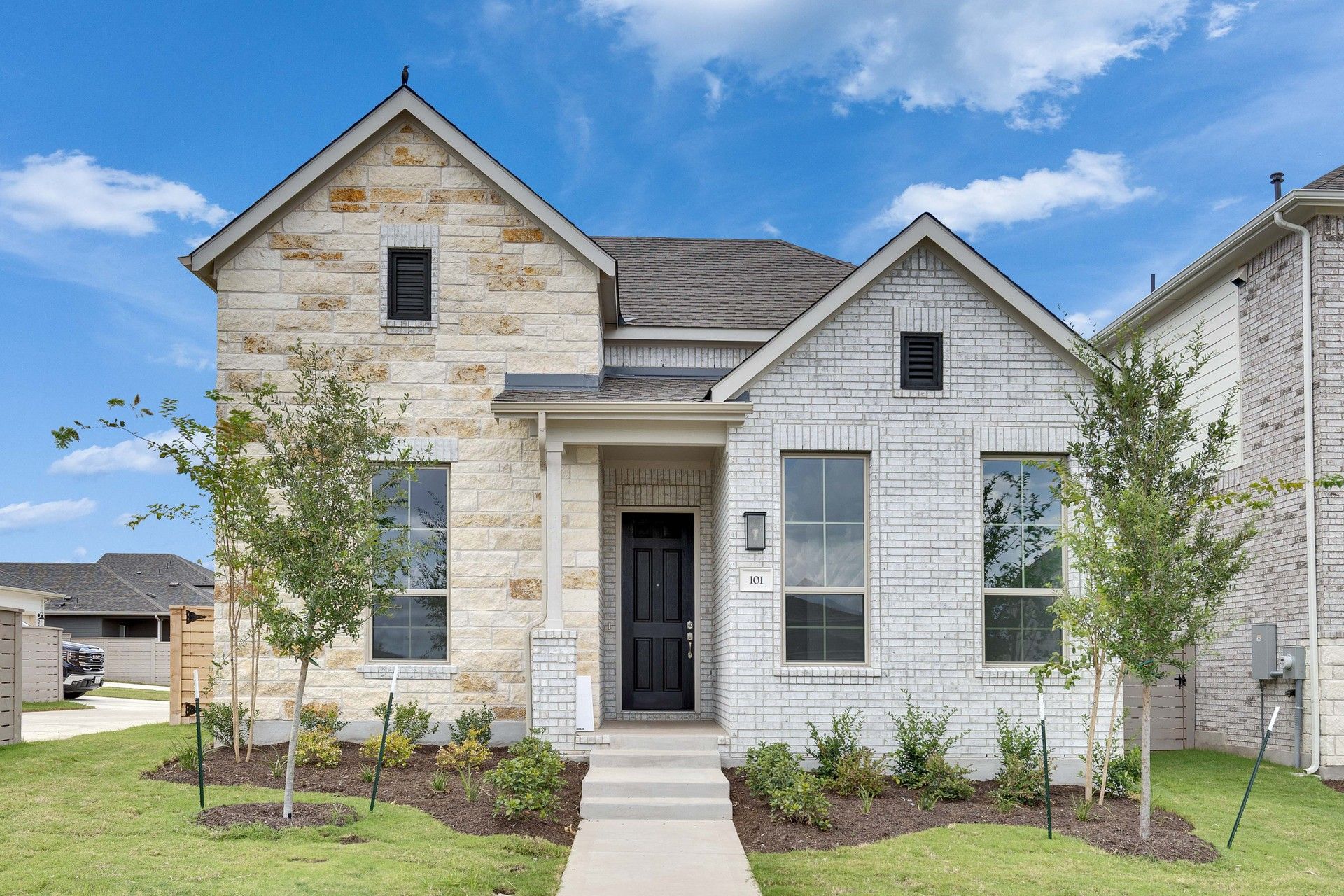 Elegant Brick and Stone Home in Flora with Gable Roof and Porch:This Flora home boasts exquisite brick and stone facade, tall windows, and elegant gable roof architecture.