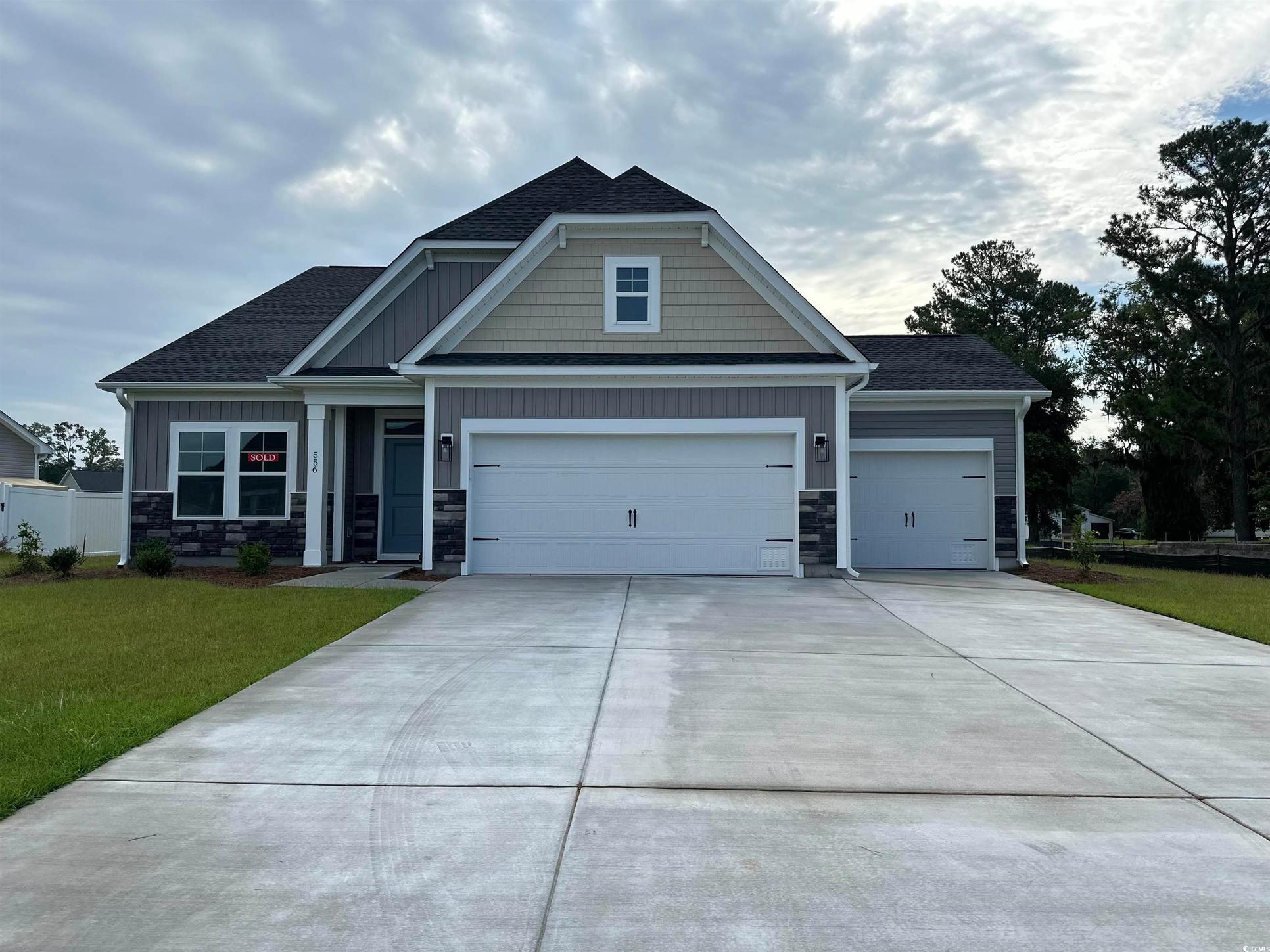 Exterior:Craftsman-style home with stone siding, a shingled roof, a front yard, and concrete driveway