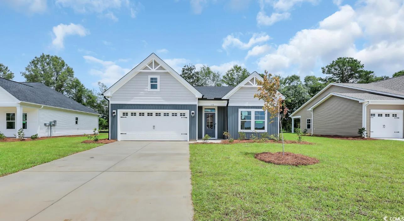 Exterior:View of front facade with board and batten siding, a garage, a front lawn, and driveway
